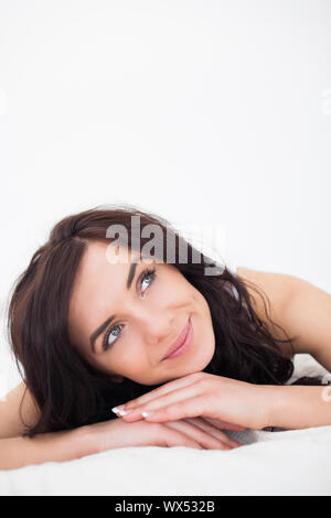 Ruhige Frau liegt auf ihrem weißen Bettdecke in ihrem Schlafzimmer Stockfoto