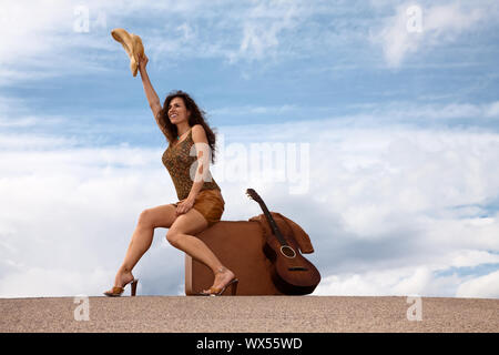 Hübsche Brünette Frau mit Koffer und Gitarre Stockfoto