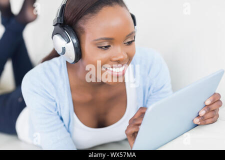 Schwarze Frau liegend auf Vorderseite mit einem Tisch-Computer in einem Wohnzimmer Stockfoto