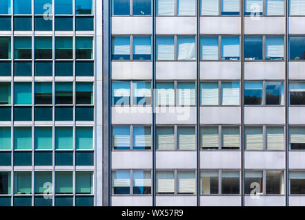 Ein Raster von Office windows in zwei moderne Gebäude aus Glas und Stahl Seite an Seite mit kontrastierenden Farben Stockfoto