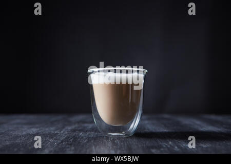 Ein Glas Tasse frisch zubereiteten Cappuccino auf einem schwarzen Holztisch mit Kopie Raum vorgestellt. Stockfoto