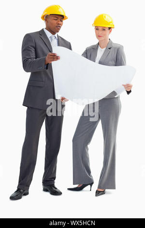 Ein Geschäftsmann und Frau mit Schutzhelmen auf einem Blatt Papier Stockfoto