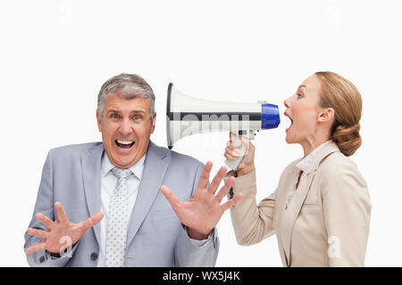 Geschäftsfrau mit einem Megafon, nachdem ihr Kollege gegen weißen Hintergrund Stockfoto
