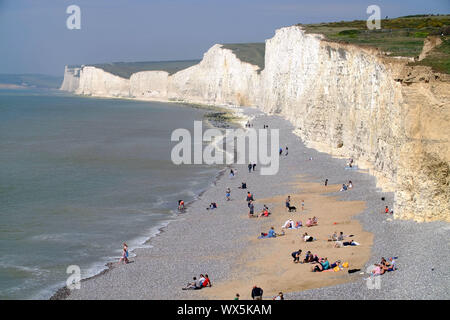 Touristen am Strand von Birling Gap, unterhalb der berühmten Sieben Schwestern Kreidefelsen. East Sussex, Großbritannien Stockfoto