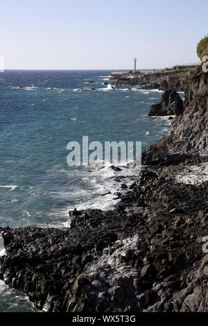 Felsen von Puerto Naos, im Hintergrund der Leuchtturm Faro de Las Hoyas in La Bombilla Stockfoto
