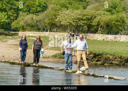 OGMORE VON MEER, WALES - April 2019: Menschen, die über die Trittsteine über den Fluss Ogwr in Ogmore vom Meer in South Wales. Ein Mann hat ein Hund Stockfoto