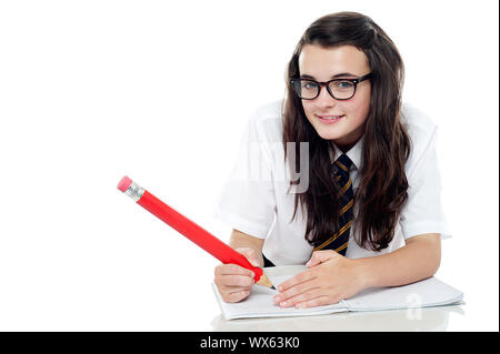 Bebrillten Schulmädchen mit langen Haaren zu studieren. Verstecken ihre Antworten während der Untersuchung Stockfoto