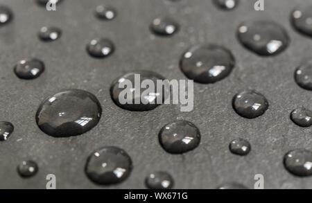 Wassertropfen auf einem schwarzen Schiefer Hintergrund. Stockfoto