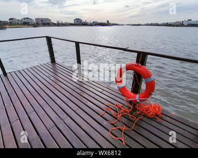 Bunte Himmel und bunten Wasser im See von holzdeck Pier mit runden Rettungsschwimmer Stockfoto