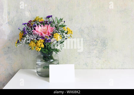 Glas Vase mit schönen bunten Strauß von Dahlia, tansies und Aster Blüten. Grunge alte Mauer Hintergrund. Feminine Hochzeit, Geburtstag Mock-up-Szene Stockfoto