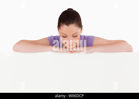 Schöne Frau posiert hinter einer Anschlagtafel beim Stehen vor einem weißen Hintergrund Stockfoto