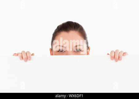Porträt einer schönen Frau posiert hinter einer Anschlagtafel beim Stehen vor einem weißen Hintergrund Stockfoto