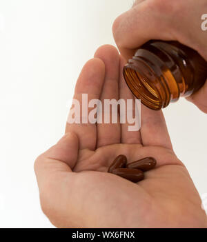 Pille Flasche und große braune Pillen in der Hand eines Mannes Stockfoto