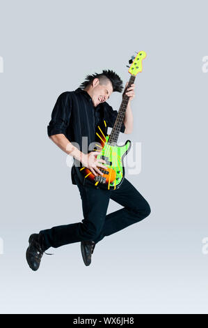 Genial Mohawk Mann springt mit seiner Gitarre im studio Stockfoto