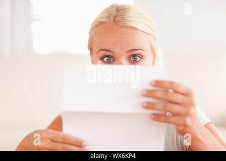 Schockiert Frau liest einen Brief in Ihrem Wohnzimmer Stockfoto
