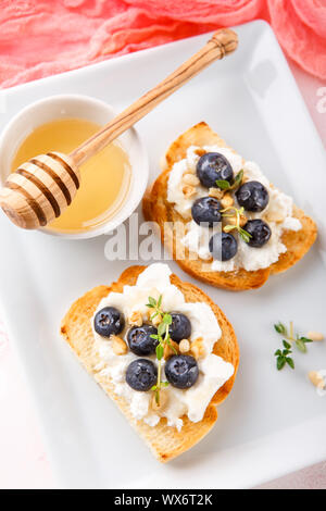 Toast mit frischen Beeren Heidelbeeren Ricotta, Thymian, Honig und Haselnüssen, serviert. Stockfoto