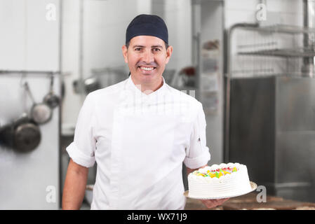 Lächelnd Konditor zeigen einen Kuchen Stockfoto