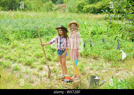 Landwirtschaft Konzept. Schwestern gemeinsam auf der Farm helfen. Anpflanzung von Gemüse. Anbau von Gemüse. Hoffnung für gute Ernte. Mädchen Pflanzen Pflanzen. Rustikale Kinder im Garten arbeiten. Anpflanzung und Bewässerung. Stockfoto