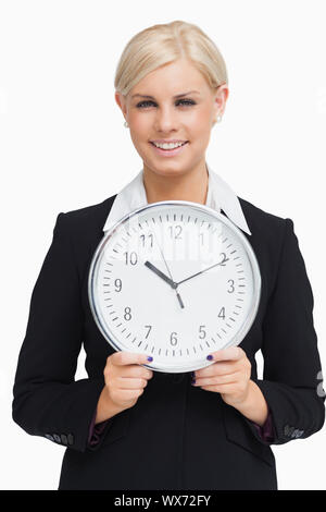 Schweren Blondine im Anzug hält eine Uhr vor weißem Hintergrund Stockfoto