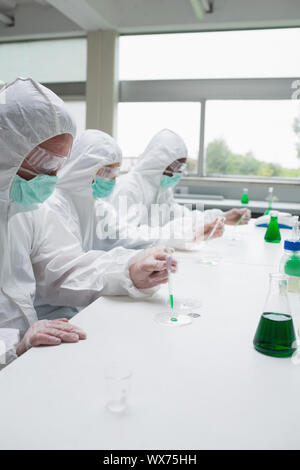 Chemiker Petrischale im Labor grünen Flüssigkeit hinzufügen Stockfoto