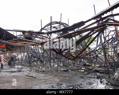 Twisted Stahlträgern nach einer Fabrik Feuer. Lager zerstört durch Feuer. Twisted Metal, Haufen von Schutt und Asche verbrannt. Stockfoto