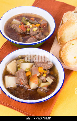 Hausgemachtes Rindfleisch und Gemüse Suppe serviert mit Gebutterten geröstetes Brot in Scheiben geschnitten. Suppe Zutaten sind Kartoffeln, Gemüse, natriumarme Brühe Stockfoto