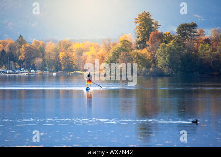Stand Up Paddling Mann im Herbst am See Stockfoto