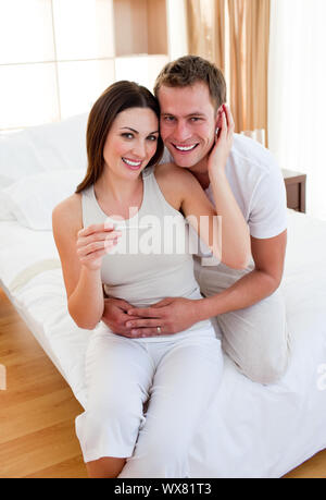 Verliebte Paare herausfinden, Ergebnisse einer Schwangerschaft Test sitzen auf dem Bett Stockfoto