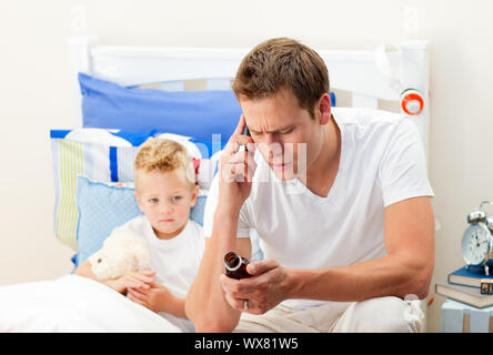 Aufmerksamer Vater am Telefon, Sirup, seinem Sohn sitzen auf dem Bett Stockfoto