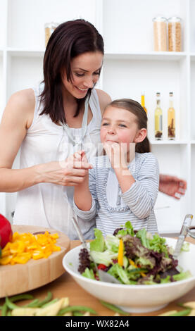 Kleines Mädchen Verkostung Salat mit ihrer Mutter in der Küche Stockfoto