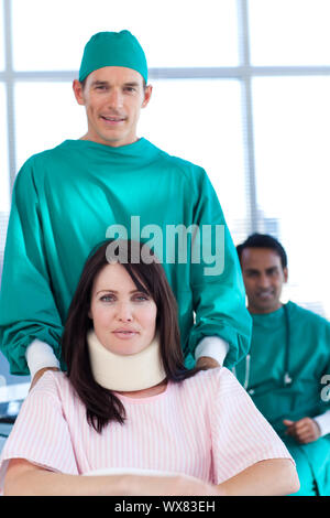 Attraktive Chirurg tragen eines Patienten auf einen Rollstuhl in einem Krankenhaus Stockfoto