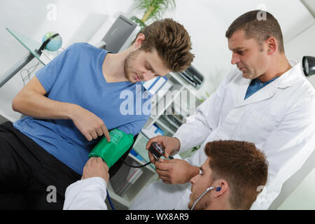 Männliche Krankenschwester befestigt Der pulsometer Bündchen am Arm des Patienten Stockfoto