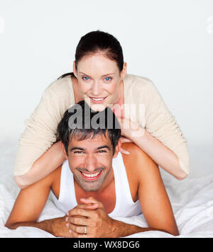 Fröhliches paar auf einem weißen Bett liegend Stockfoto