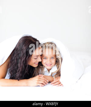 Schöne Mutter und ihre Tochter auf dem Bett in die Kamera schaut Stockfoto