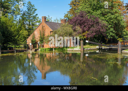 Blick auf New Haw Schloss und der historische Schleusenwärter Cottage auf dem Fluss Wey (Wey Navigationen) bei New Haw, Surrey, Südost England Stockfoto