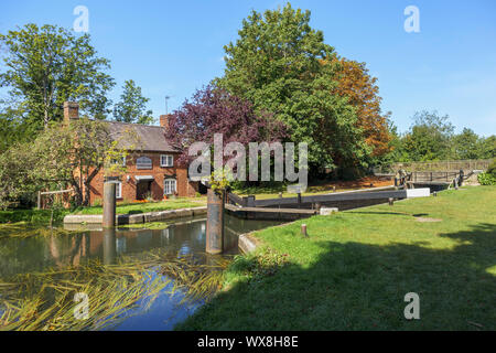 Blick auf New Haw Schloss und der historische Schleusenwärter Cottage auf dem Fluss Wey (Wey Navigationen) bei New Haw, Surrey, Südost England Stockfoto