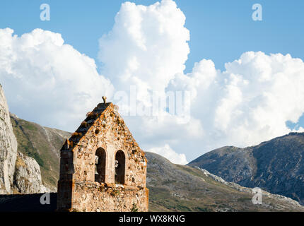 Eine kleine steinerne Kirche mit einem Glockenturm mit einer leicht bewölkt blauer Himmel im Hintergrund, während Sie im Sommer Stockfoto