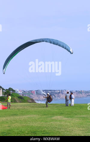 LIMA, PERU - 19. MÄRZ 2012: Nicht identifizierte Person mit einem Gleitschirm auf der Küste von Miraflores mit Blick auf die Küste von Miraflores und Barranco Stockfoto