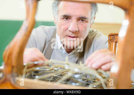 Mann, die Polsterung Stuhl in seiner Werkstatt Stockfoto