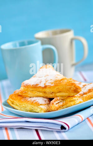 Apple-Umsätze-Gebäck mit Kaffeetassen im Hintergrund Stockfoto