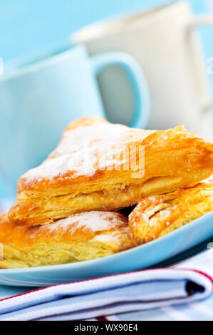 Apple-Umsätze-Gebäck mit Kaffeetassen im Hintergrund Stockfoto