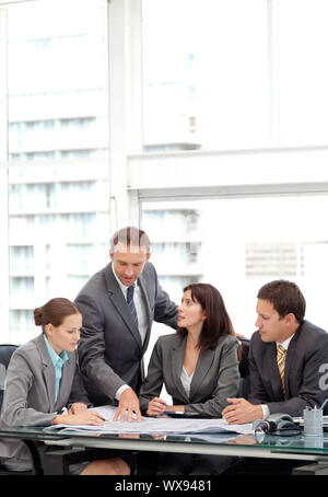 Erfolgreiche Manager zeigt einen Plan zu seiner Mannschaft während einer Sitzung im Büro Stockfoto