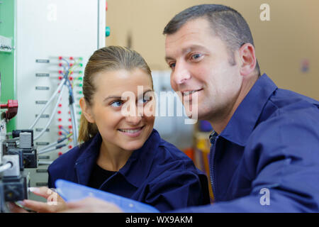 Ingenieur mit weiblichen Lehrling, wie eine Maschine zu bedienen. Stockfoto