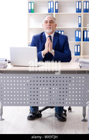 Alter Geschäftsmann Yoga Übungen im Büro Stockfoto