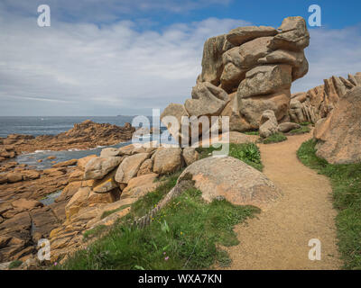Pfad zwischen riesigen Felsbrocken über die schroffen Felsen über dem Meer entlang der Bretonischen rosa Granit Küste, der Côte de Granit Rose, in der Nähe von Ploumanach, Frankreich. Stockfoto