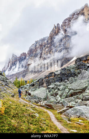 Unbekannter Wanderer auf Opabin Trail am Lake O'Hara mit schweren Wolken absteigend auf dem Berg Shaffer an der Kanadischen Rockies von Yoho National Park in Brit Stockfoto