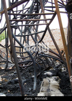 Twisted Stahlträgern nach einer Fabrik Feuer. Lager zerstört durch Feuer. Twisted Metal, Haufen von Schutt und Asche verbrannt. Stockfoto