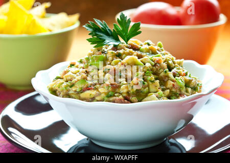 Guacamole-Salat in Schüssel weiß mit Petersilie obenauf angeordnet Stockfoto