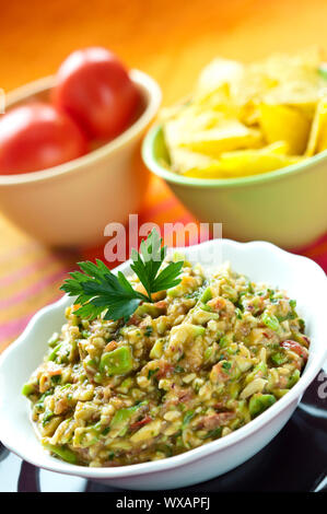 Guacamole-Salat in Schüssel weiß mit Petersilie obenauf angeordnet Stockfoto