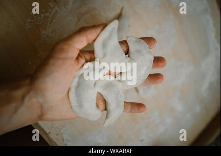 Frau Hände machen einen feuchten Knödel. Auf dem hölzernen Tisch. Stockfoto